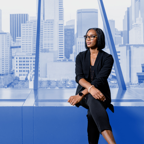 Woman sitting on a bench with a city view in the background. 