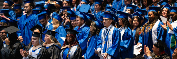 Multiple graduates dressed in regalia standing during the ceremony.