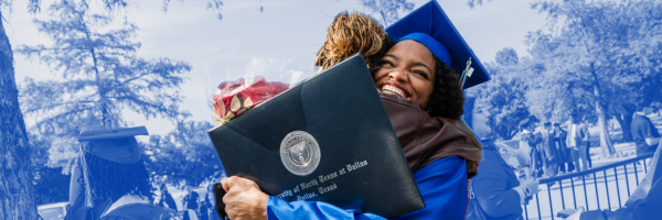 Graduate hugging a loved one with diploma in hand. 