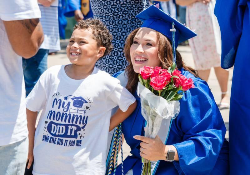 A Graduate Smiles With Her Son After Receiving Flowers in a Tender Family Moment