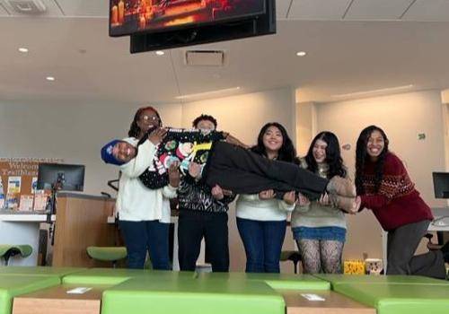 Chrishna Brooks (far left) and Other Student Solutions Center Workers Hold a Colleague During a Fun Moment