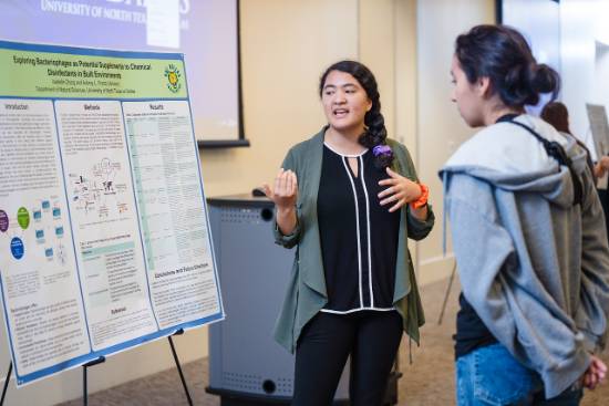 Isabelle Chung Speaks with a Fellow Student About Her Research of Chemical Disinfectants