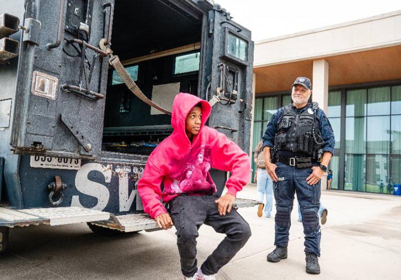A Student Sits on the Bumper of a SWAT Truck