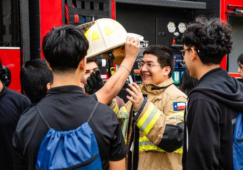 A High School Student Tries On a Firefighter's Helmet and Gear as Classmates Watch
