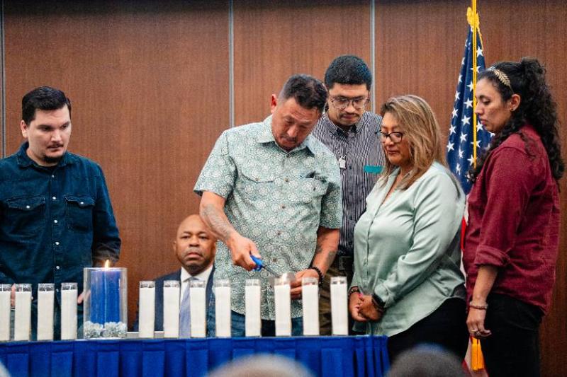 Jonathan Suarez's Father Lights a Candle in Memory of His Son, As His Wife and Jonathan's Siblings Stand in Support