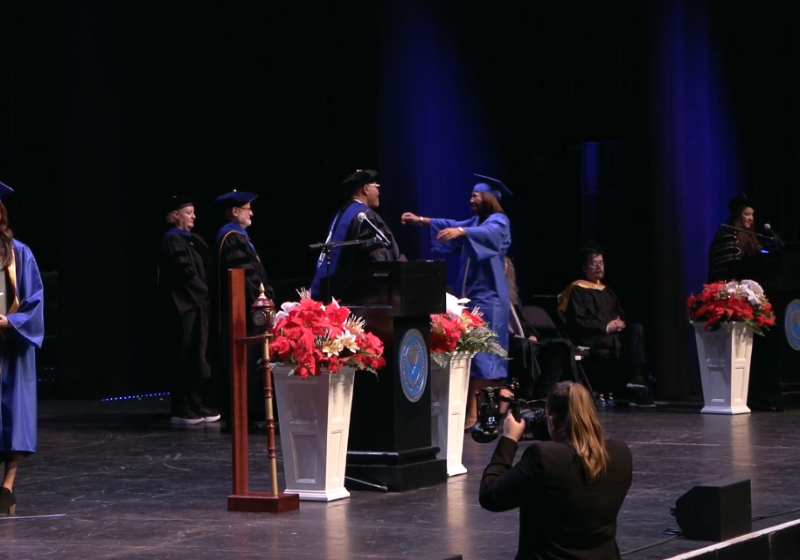 Cora Black Reaches Out to Hug Her Father Albert as She Crosses the Commencement Stage on Dec. 16, 2025