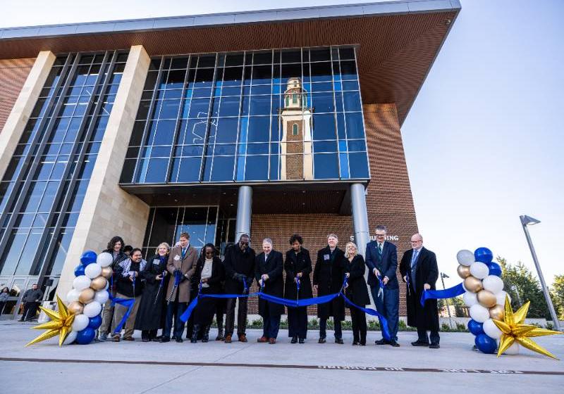 University Leaders and Other Dignitaries Cut the Ribbon to Celebrate the New STEM Building. Reflected in the Windows is the Ryan Tower.