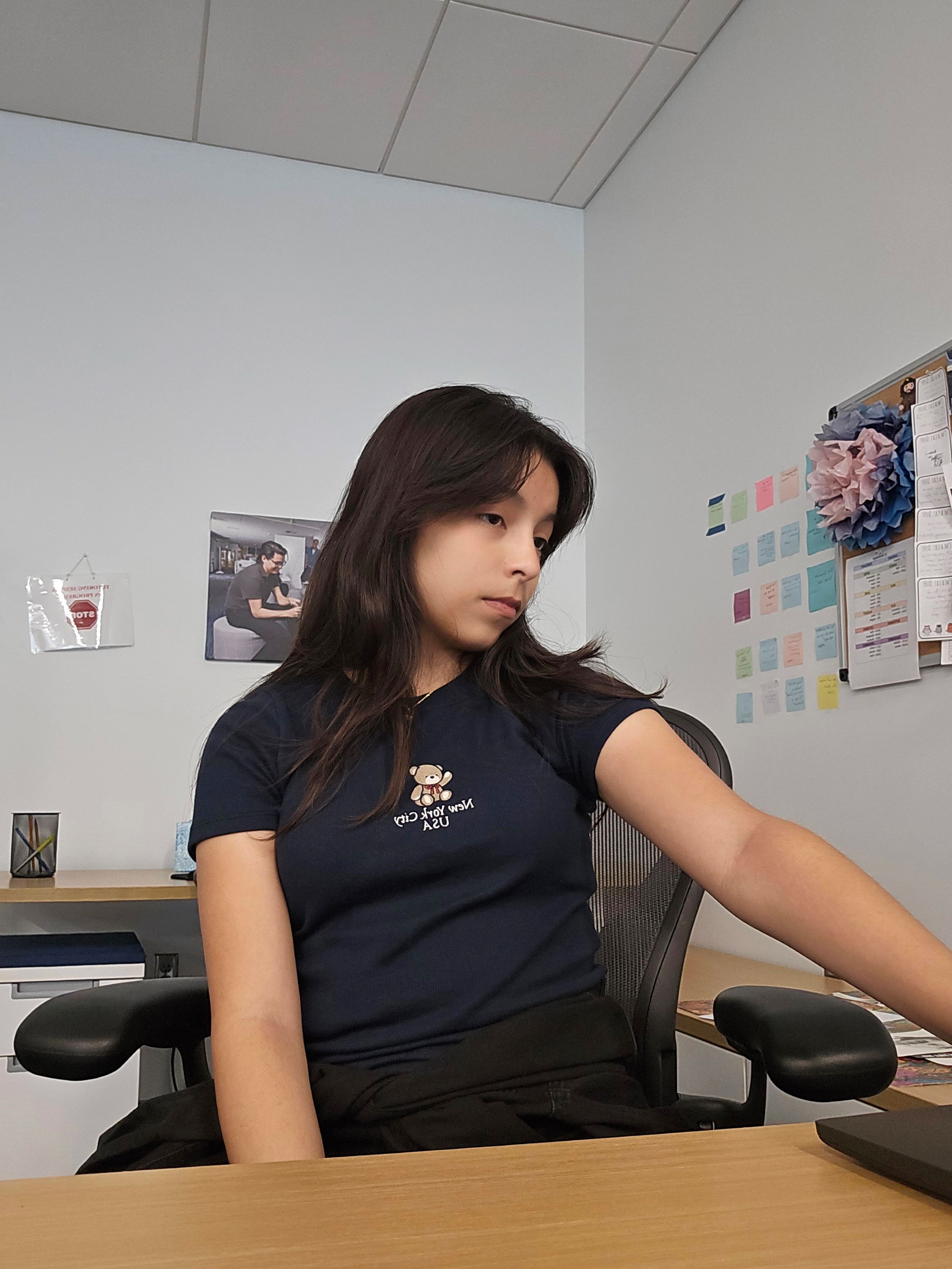 young woman in a navy blue shirt with a small teddy stitched into the fabric