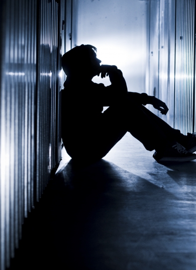 person huddled against wall in darkness