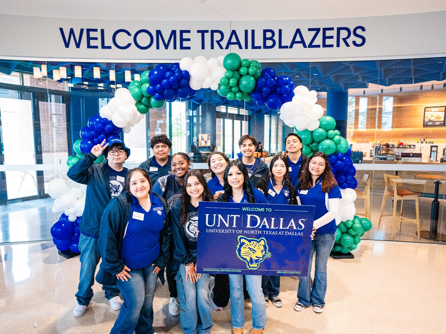 Group of students smiling and holding a UNT Dallas sign